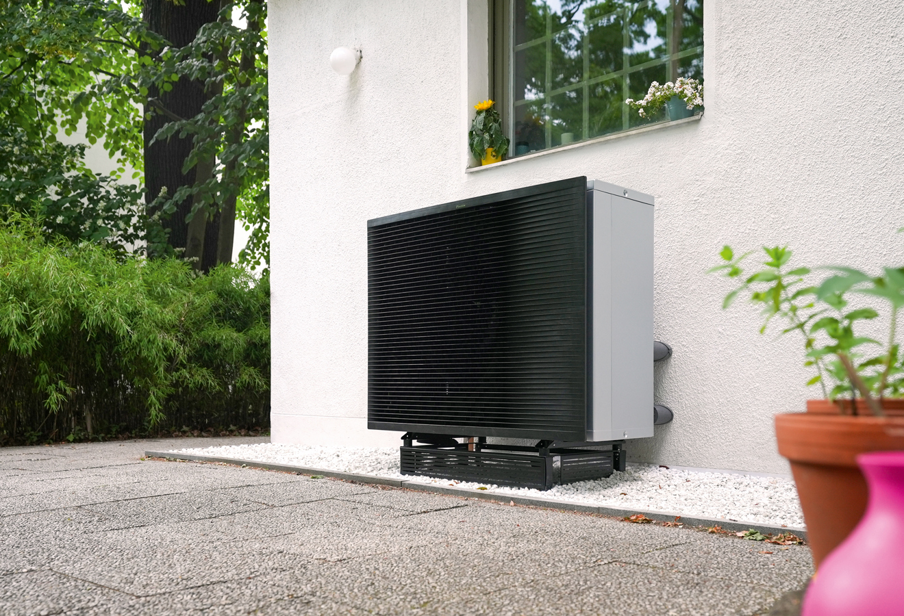 Kompakte Daikin Wärmepumpe im Garten vor einem Wohnhaus
