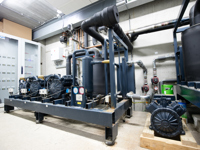 Detailansicht einer Industriekälteanlage mit Kompressoren und Rohrleitungen.